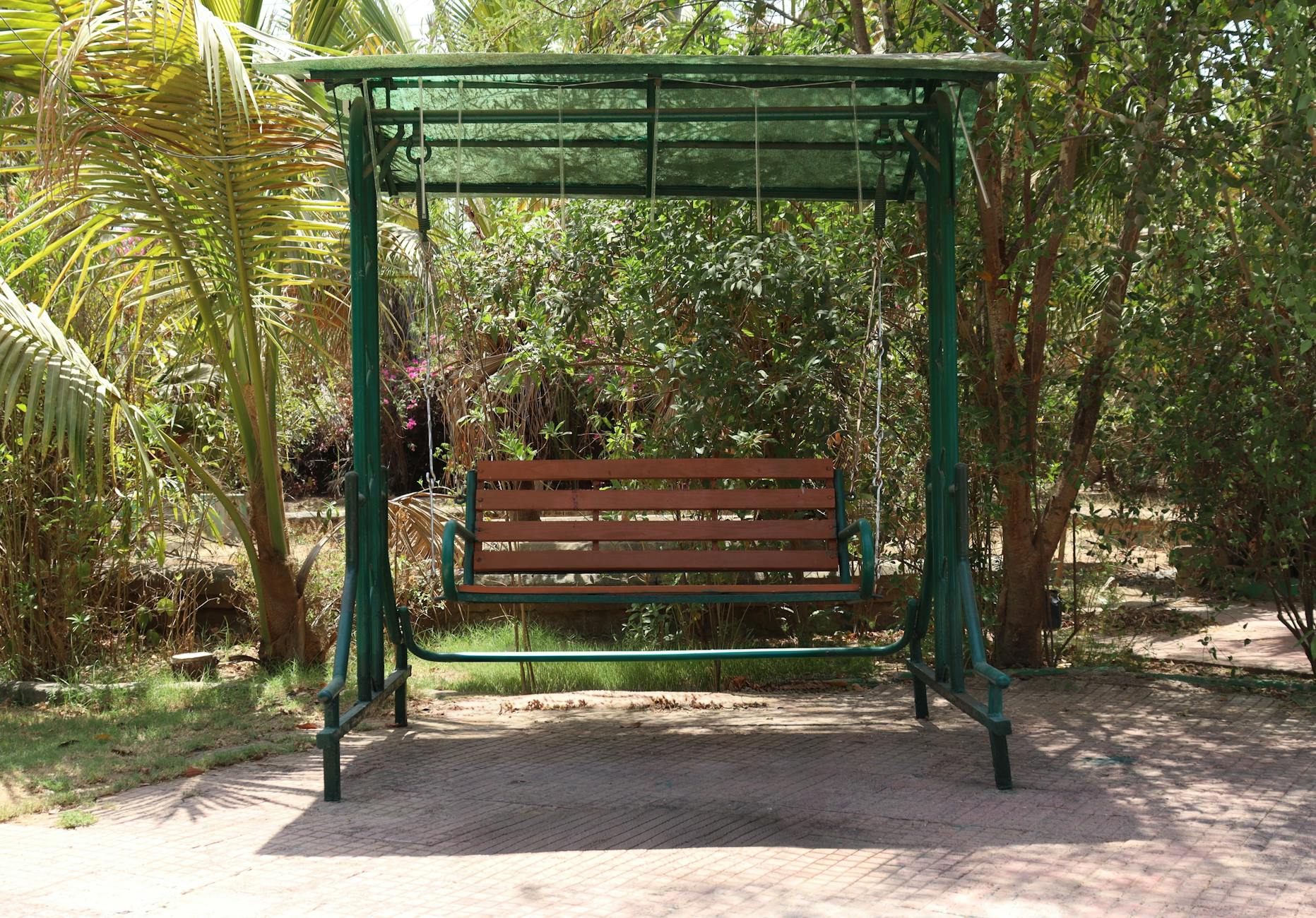 Konstrukcja pod huśtawkę: jak policzyć rozstaw i uniknąć przechyłów Drewniana huśtawka ogrodowa stojąca wśród bujnej zieleni