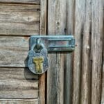 Wieszak na klucze z drewna: szybki projekt Drewniane, rustykalne drzwi zamknięte na metalową kłódkę i zasuwę