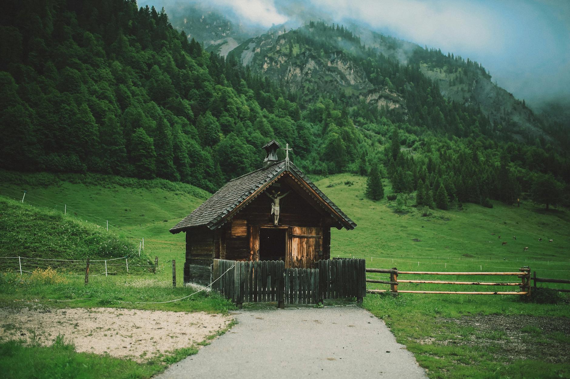 Drewniany dom w dolinie u podnóża mglistych gór