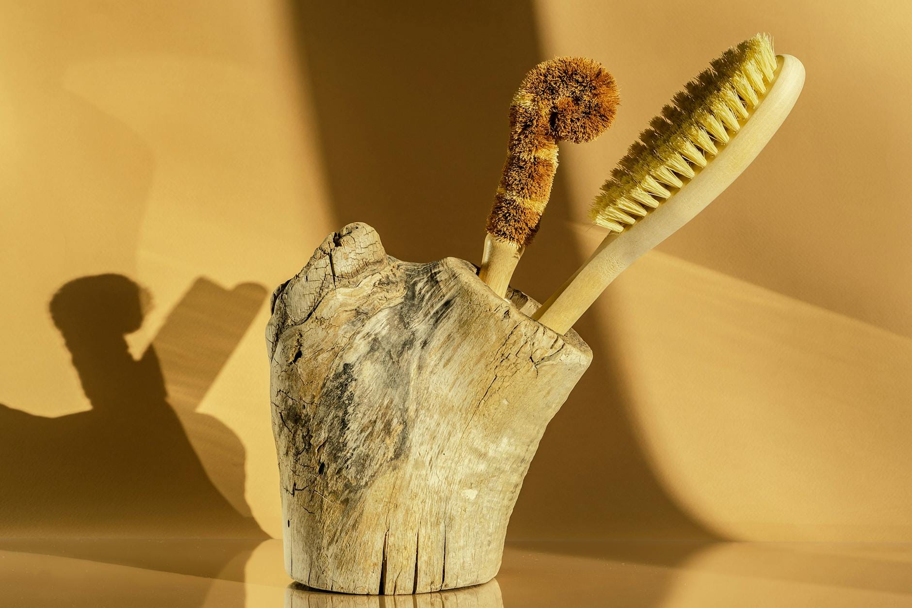 Naturalne szczotki z włosia w drewnianym stojaku na tle ciepłej ściany