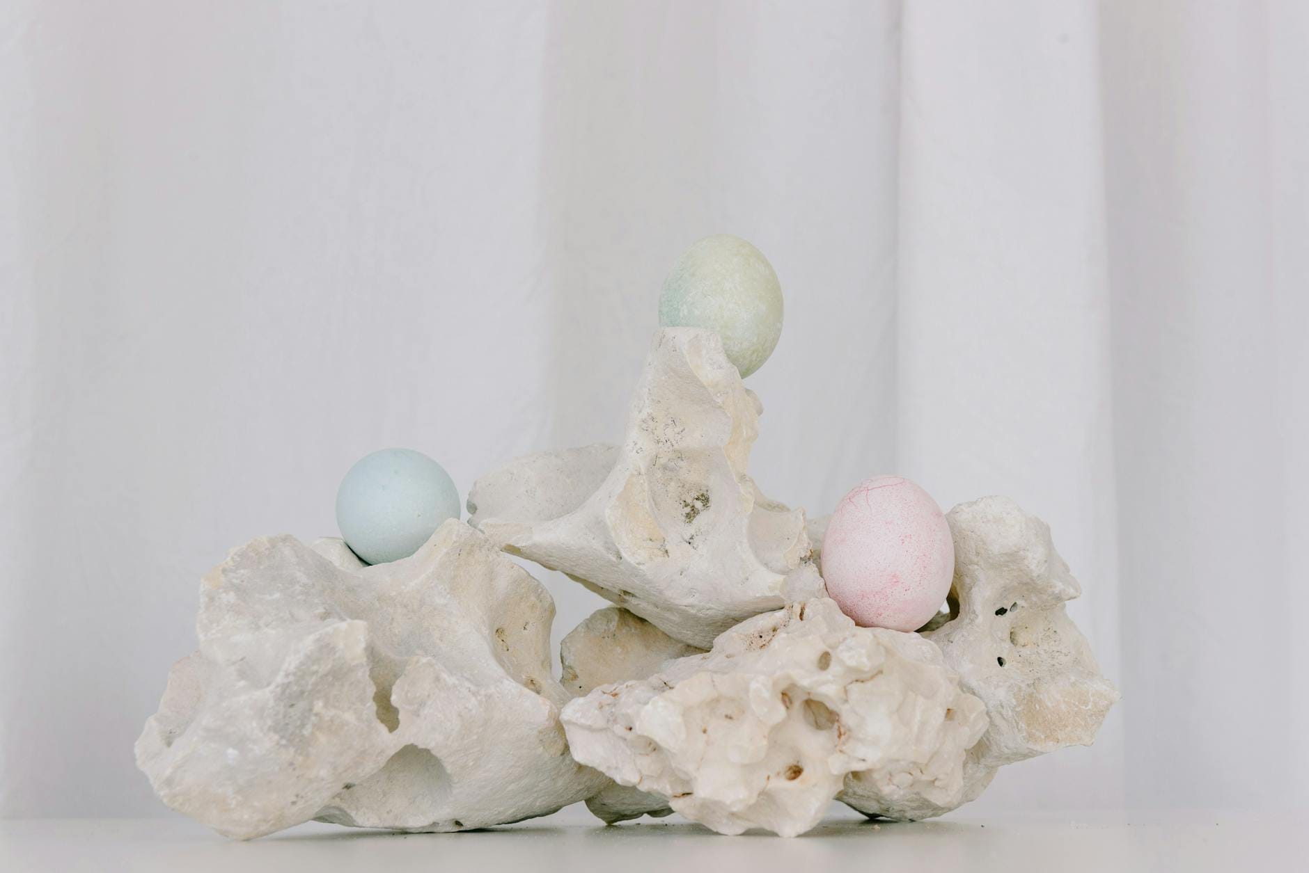 Pastelowe pisanki ułożone na białych, chropowatych kamieniach