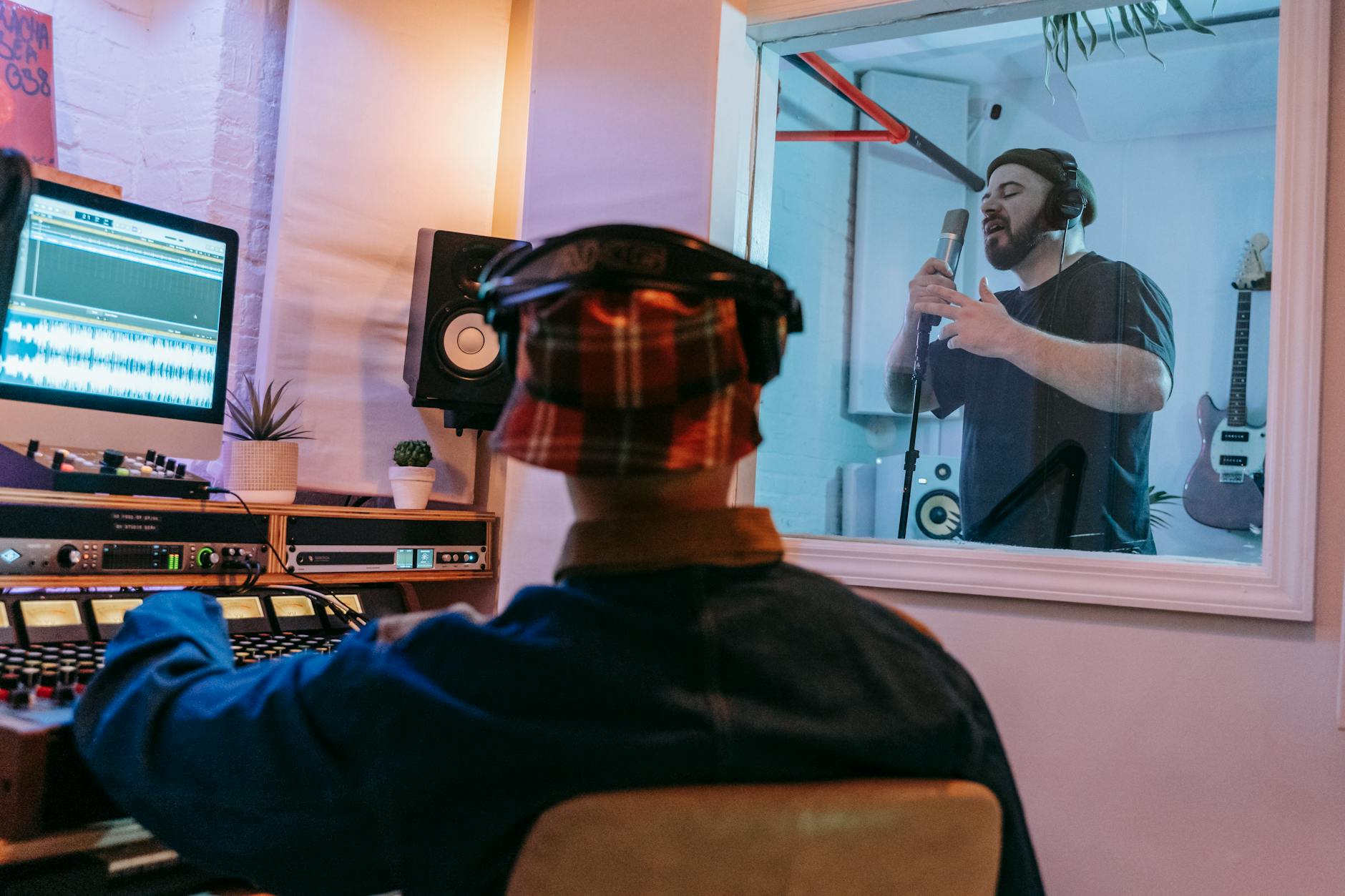 Wokalistka nagrywająca w studiu z realizatorem dźwięku w tle Wokalistka nagrywająca w studiu z realizatorem dźwięku w tle