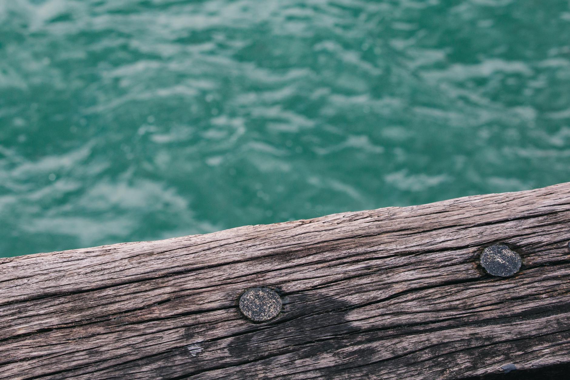 Zbliżenie desek drewnianego pomostu nad turkusową wodą