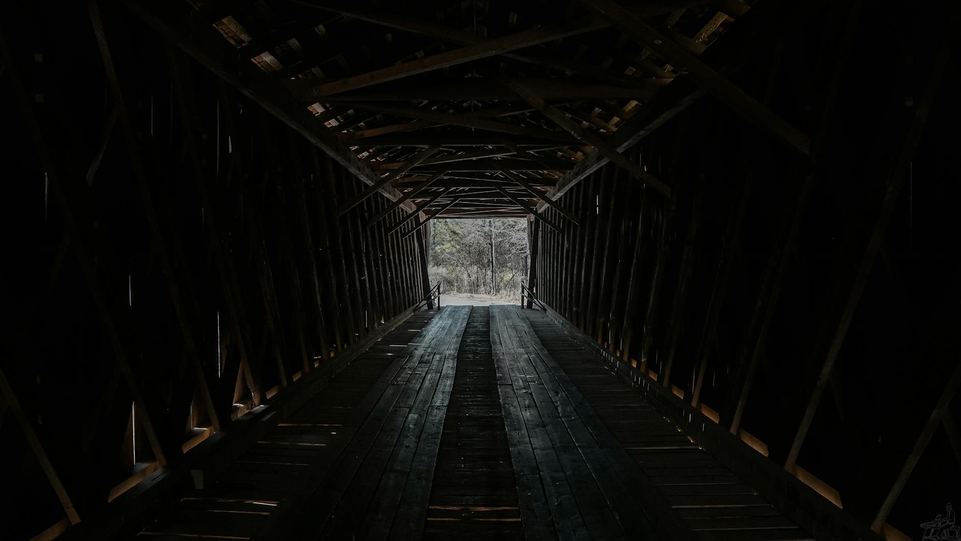 Drewniany kryty most z widocznym światłem na końcu wnętrza