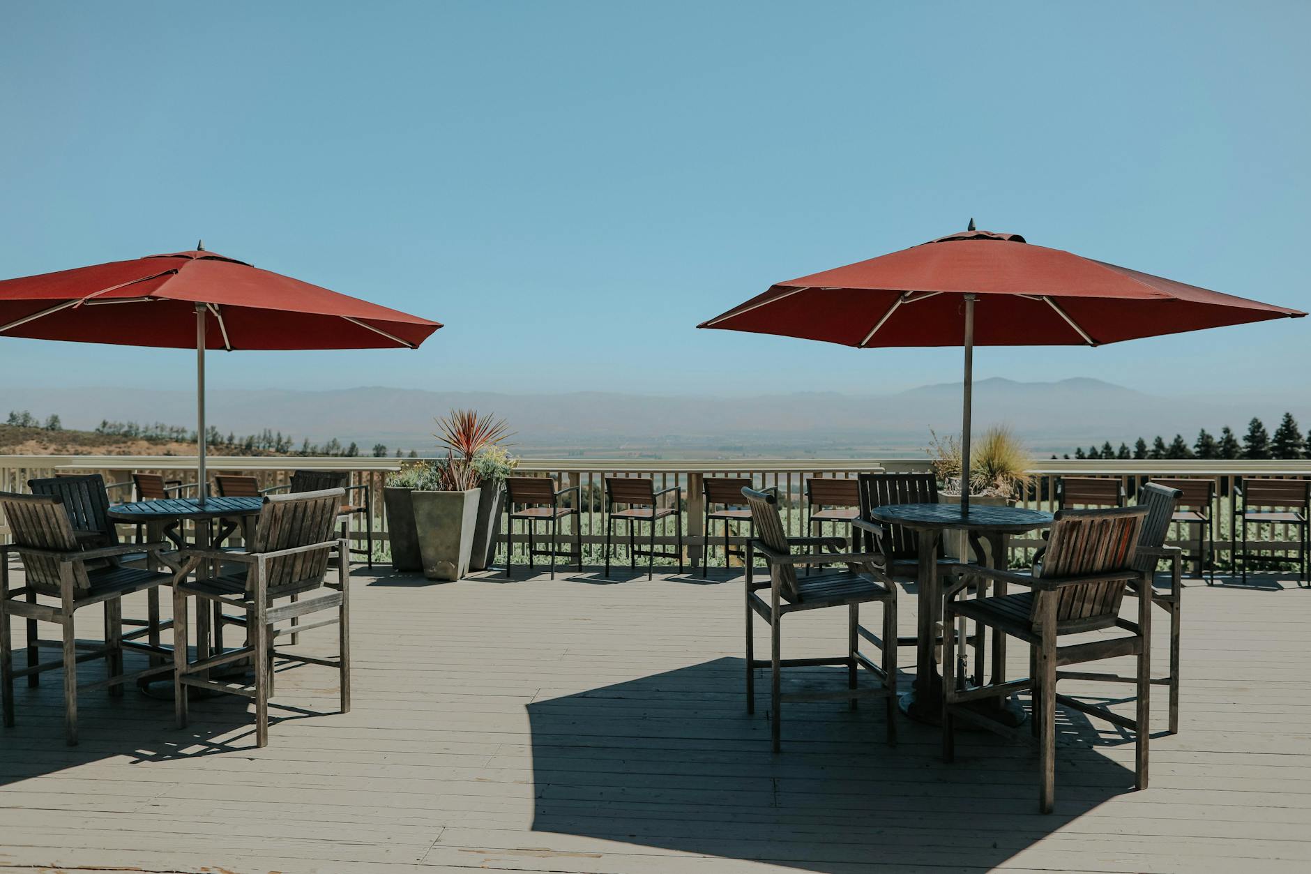 Drewno na taras bez tajemnic: modrzew, egzotyki i termodrewno w zestawieniu trwałości i pielęgnacji Drewniany taras z eleganckimi meblami i czerwonymi parasolami