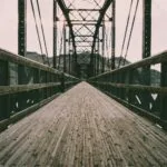 Jakie drewno wybierano do dawnych mostów i przepraw? Drewniany most wiszący nad rzeką z widocznymi detalami konstrukcji