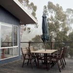 Łączniki ukryte w drewnie: estetyka tarasu i elewacji bez widocznych śrub Drewniany taras z nowoczesnymi meblami ogrodowymi we mgle