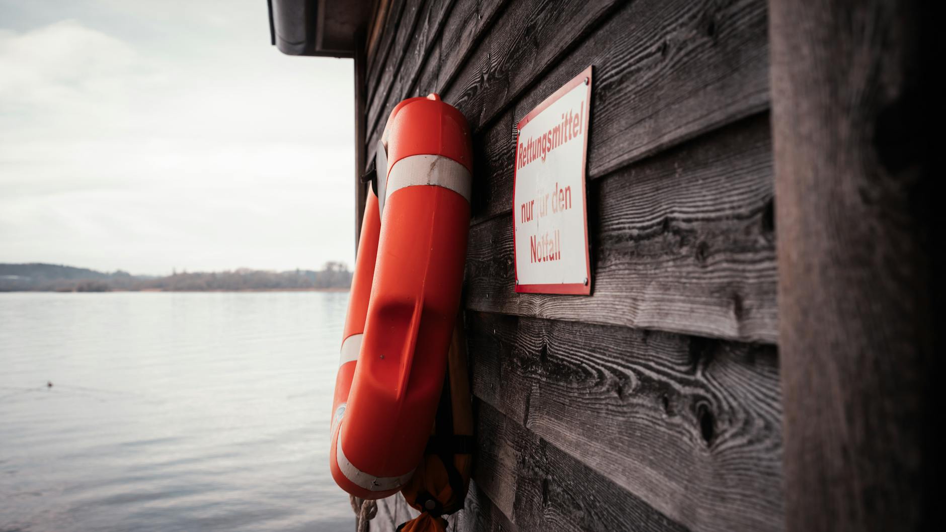 Pomarańczowe koło ratunkowe na drewnianym domku nad jeziorem