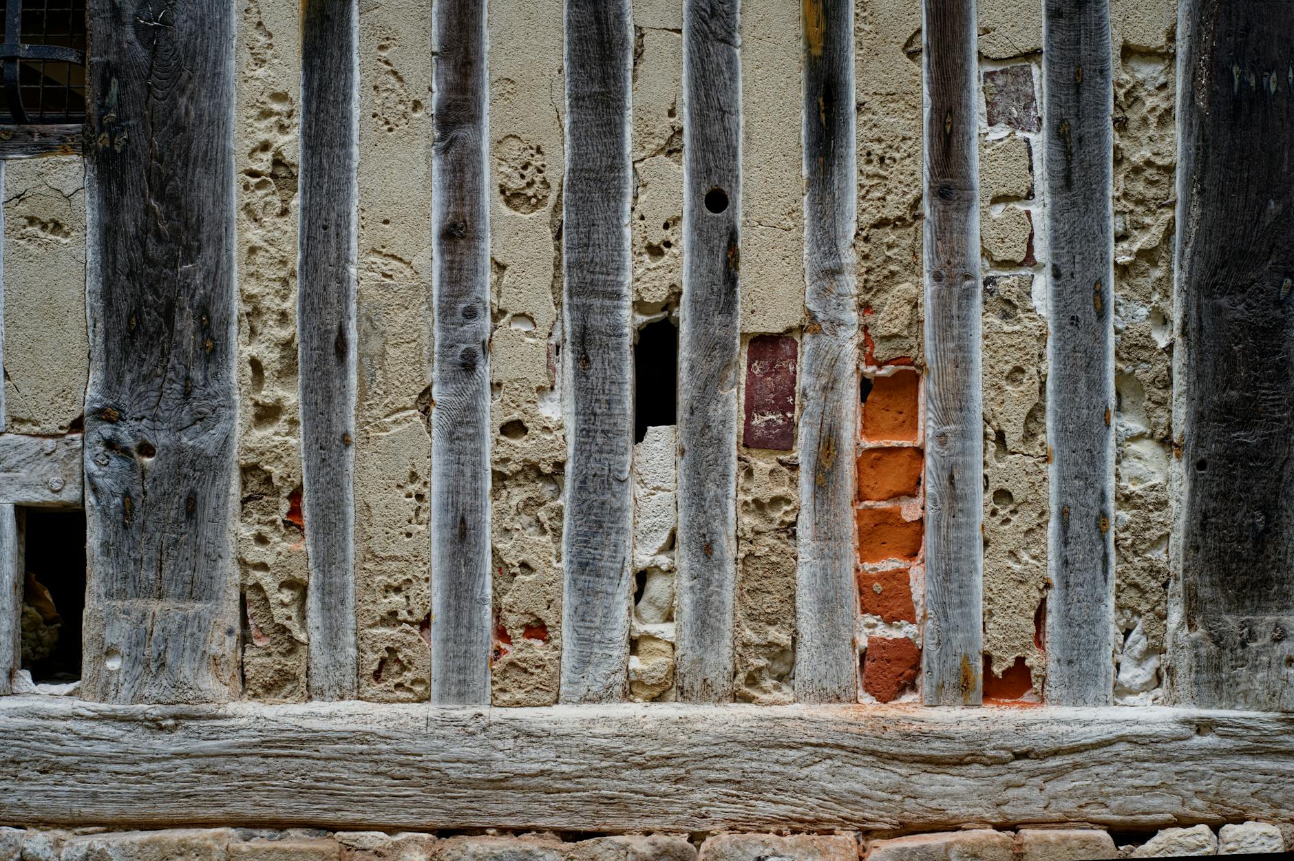 Drewno kontra cegła: dlaczego w różnych epokach wygrywał inny materiał? Zbliżenie ściany z drewnianymi belkami i odsłoniętą cegłą