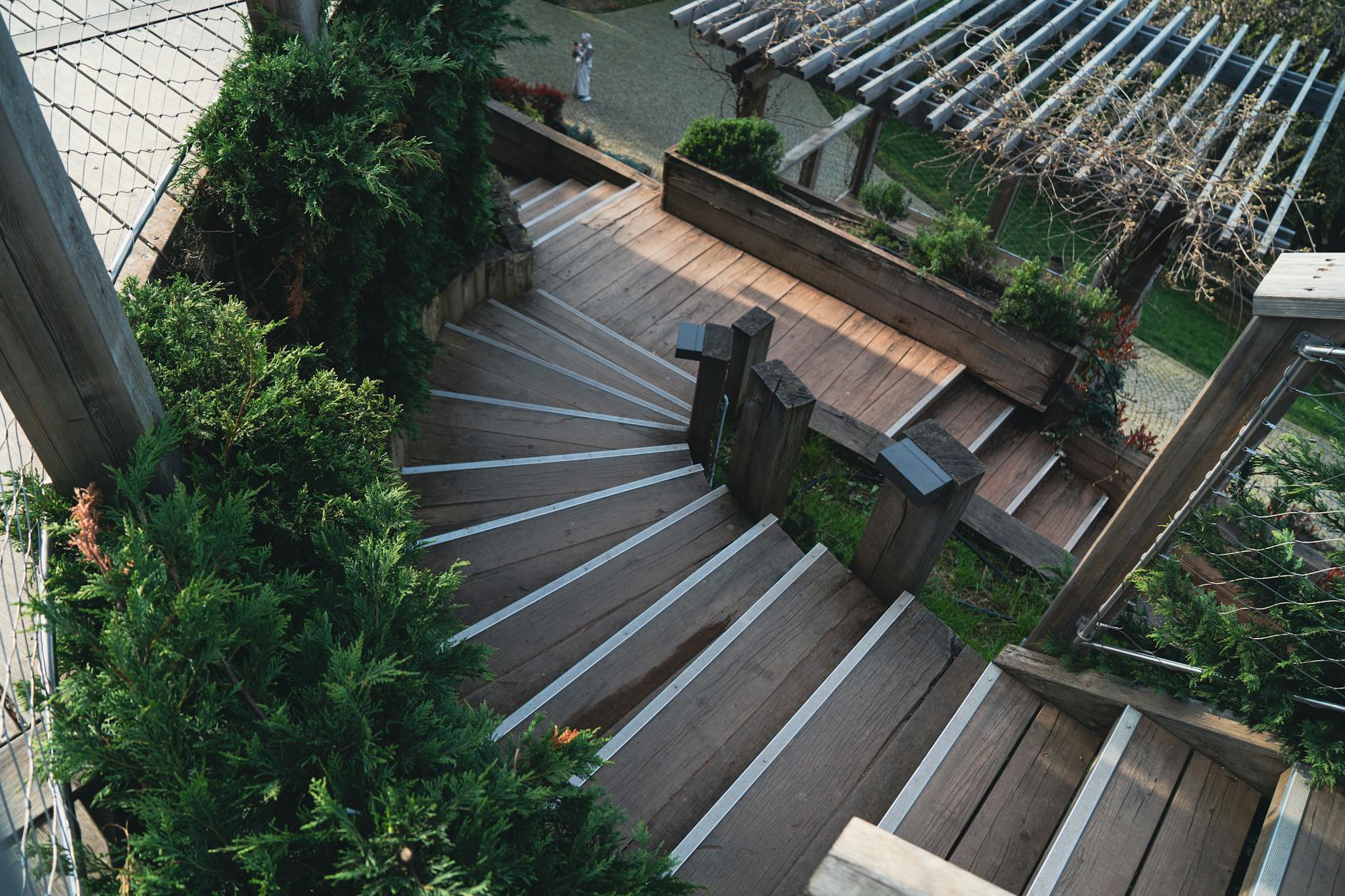 Drewniane schody tarasowe w ogrodzie otoczone bujną zielenią