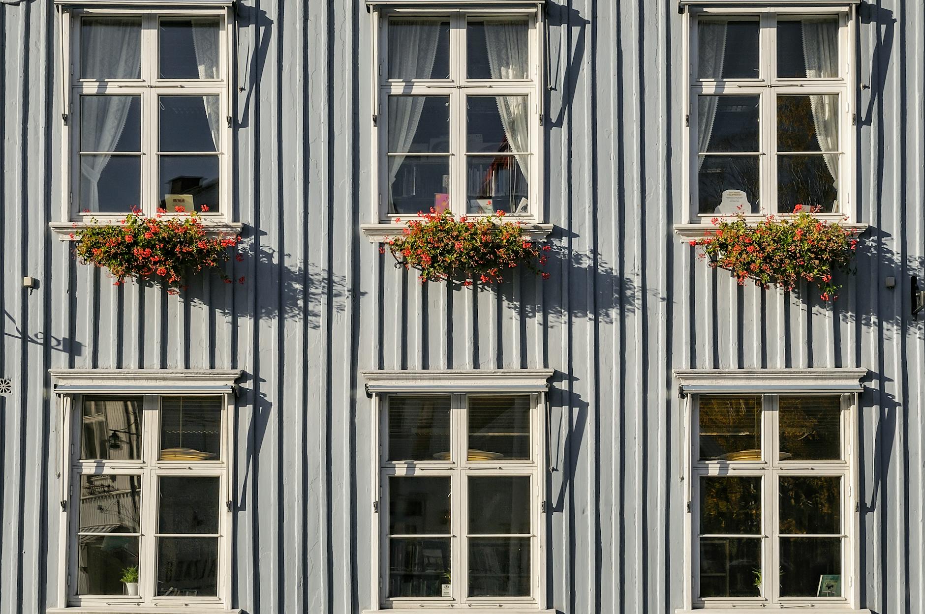 Elewacja drewnianego domu ze skrzynkowymi oknami i kwiatami