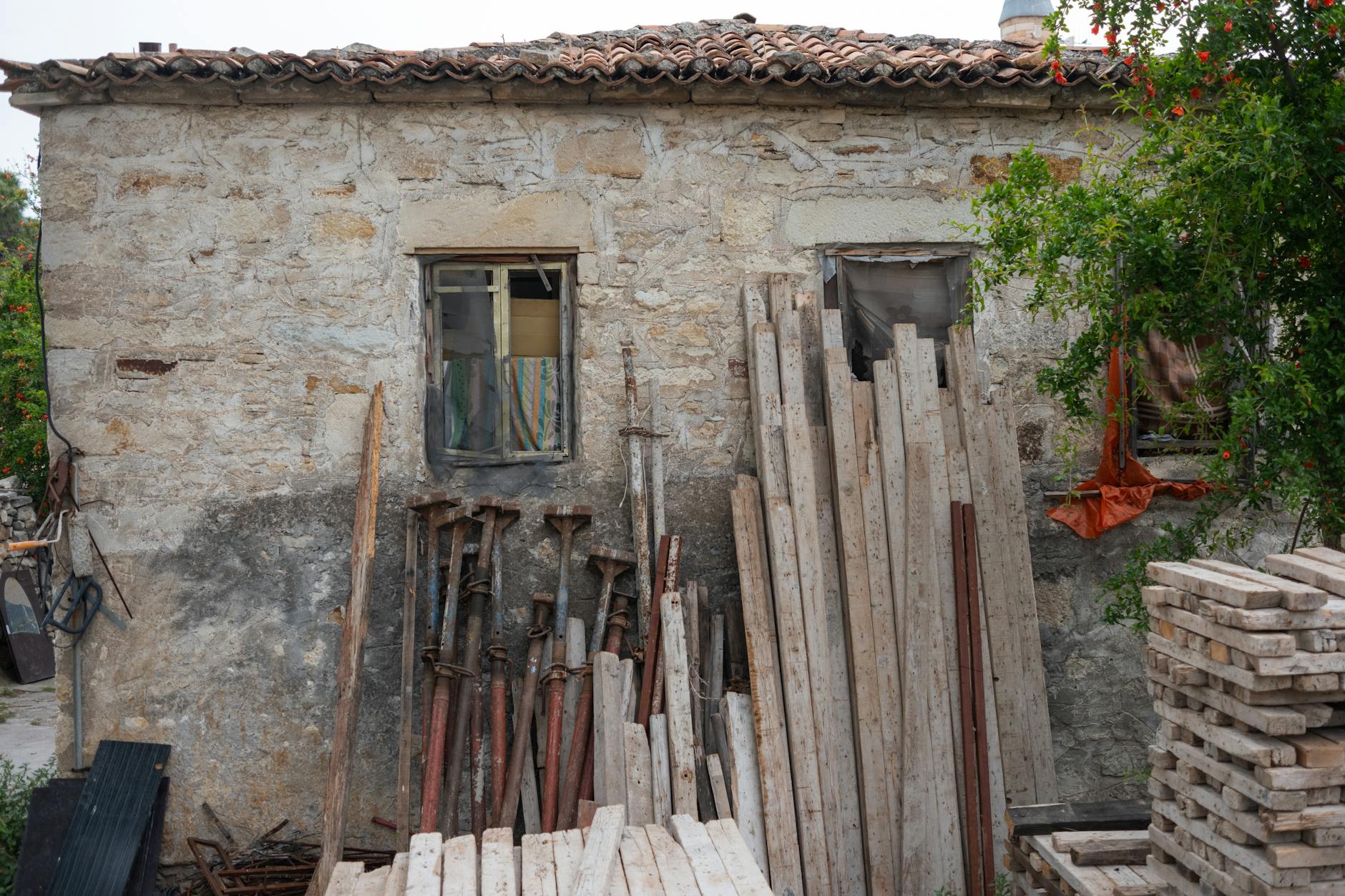 Kamienny dom w Foça otoczony materiałami budowlanymi i zielenią