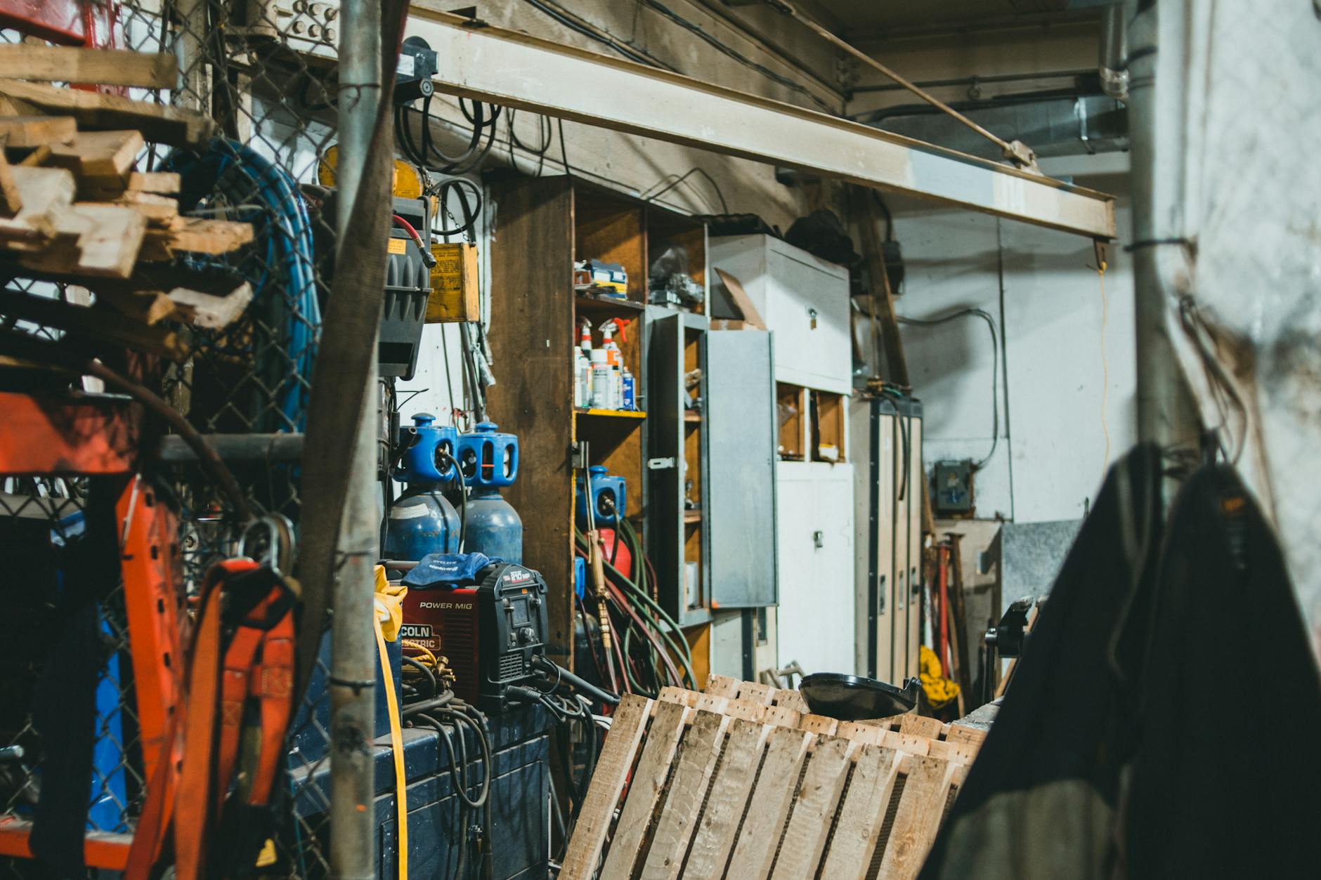 Zagracony warsztat stolarski z narzędziami, sprzętem i butlami gazowymi