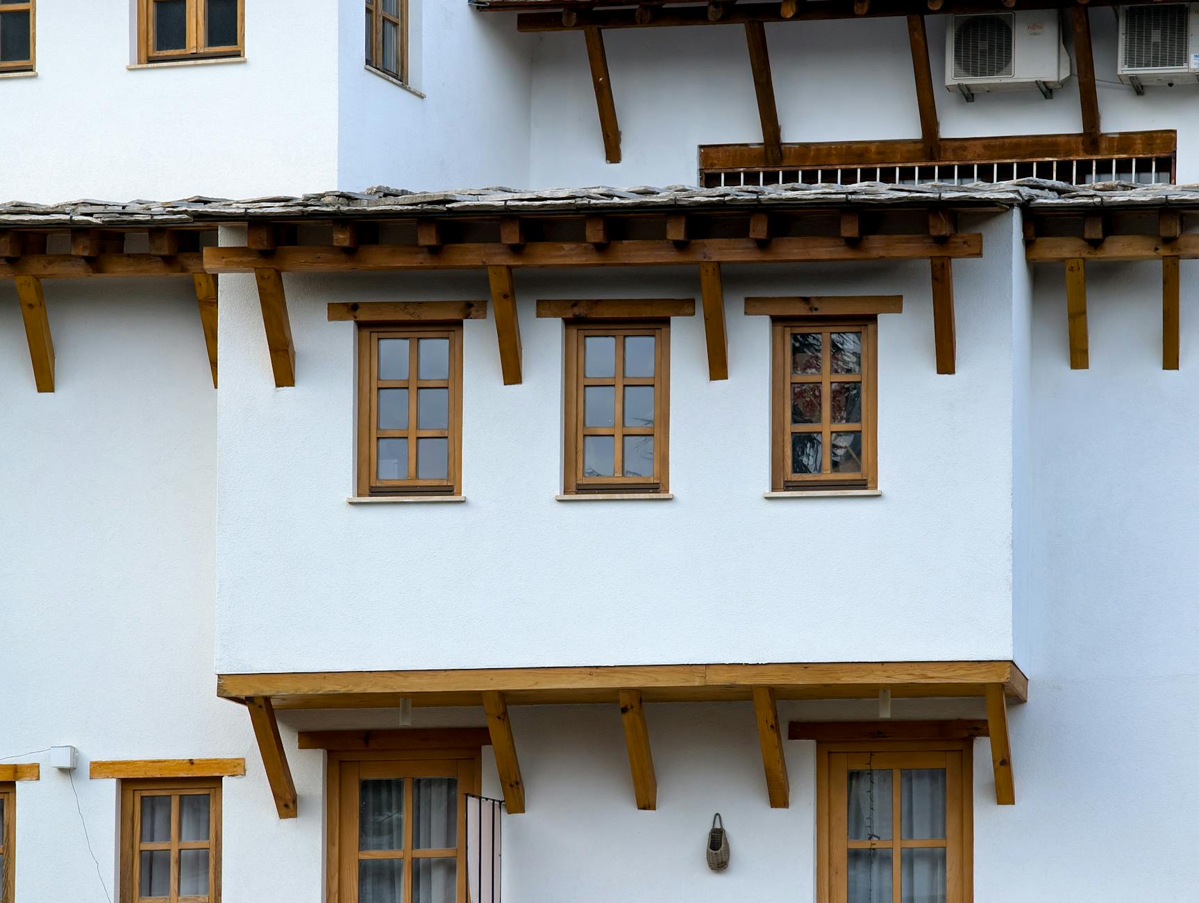 Zbliżenie białego domu z drewnianymi oknami i okapem dachu