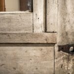 Zbliżenie starego drewnianego skrzydła z przerdzewiałymi zawiasami