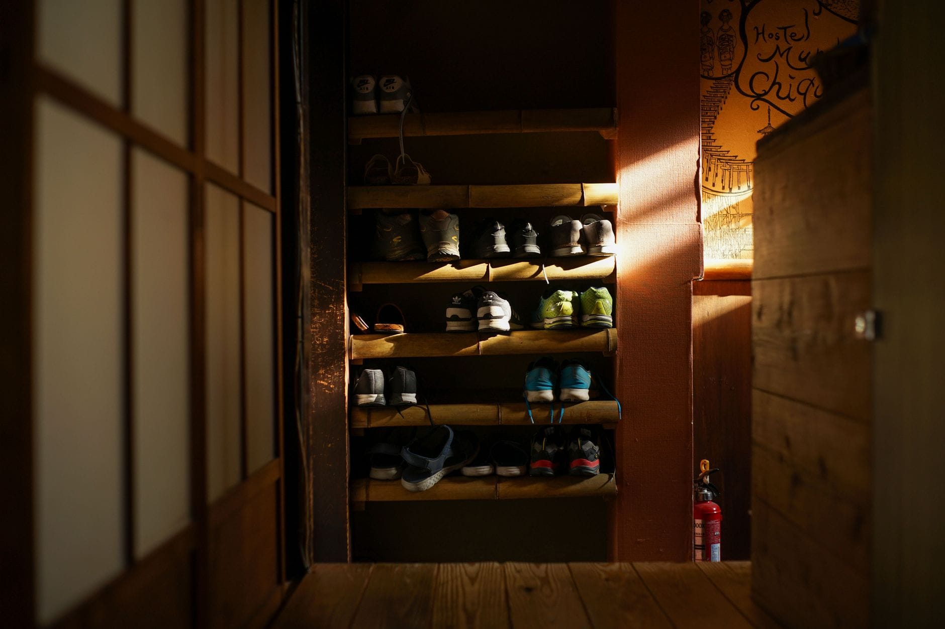 Drewniana szafka na buty z poukładanymi sneakersami w japońskim domu