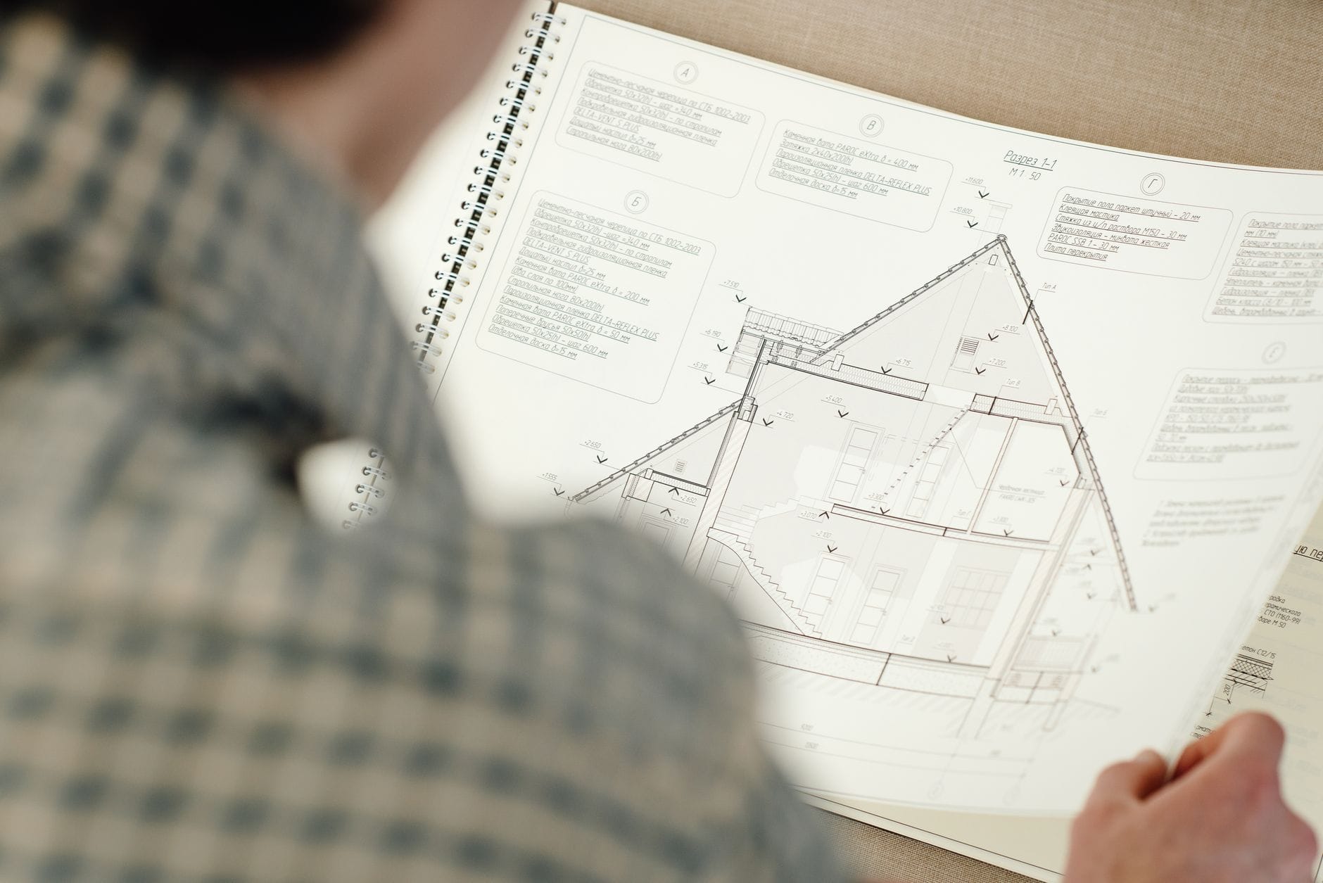 Osoba analizująca architektoniczny plan domu z detalami projektu