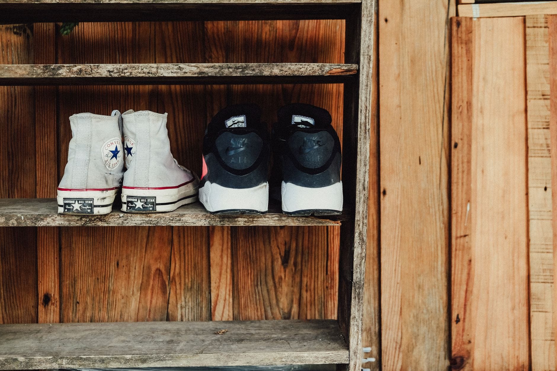 Rustykalna drewniana półka na buty z trampkami Converse i Nike