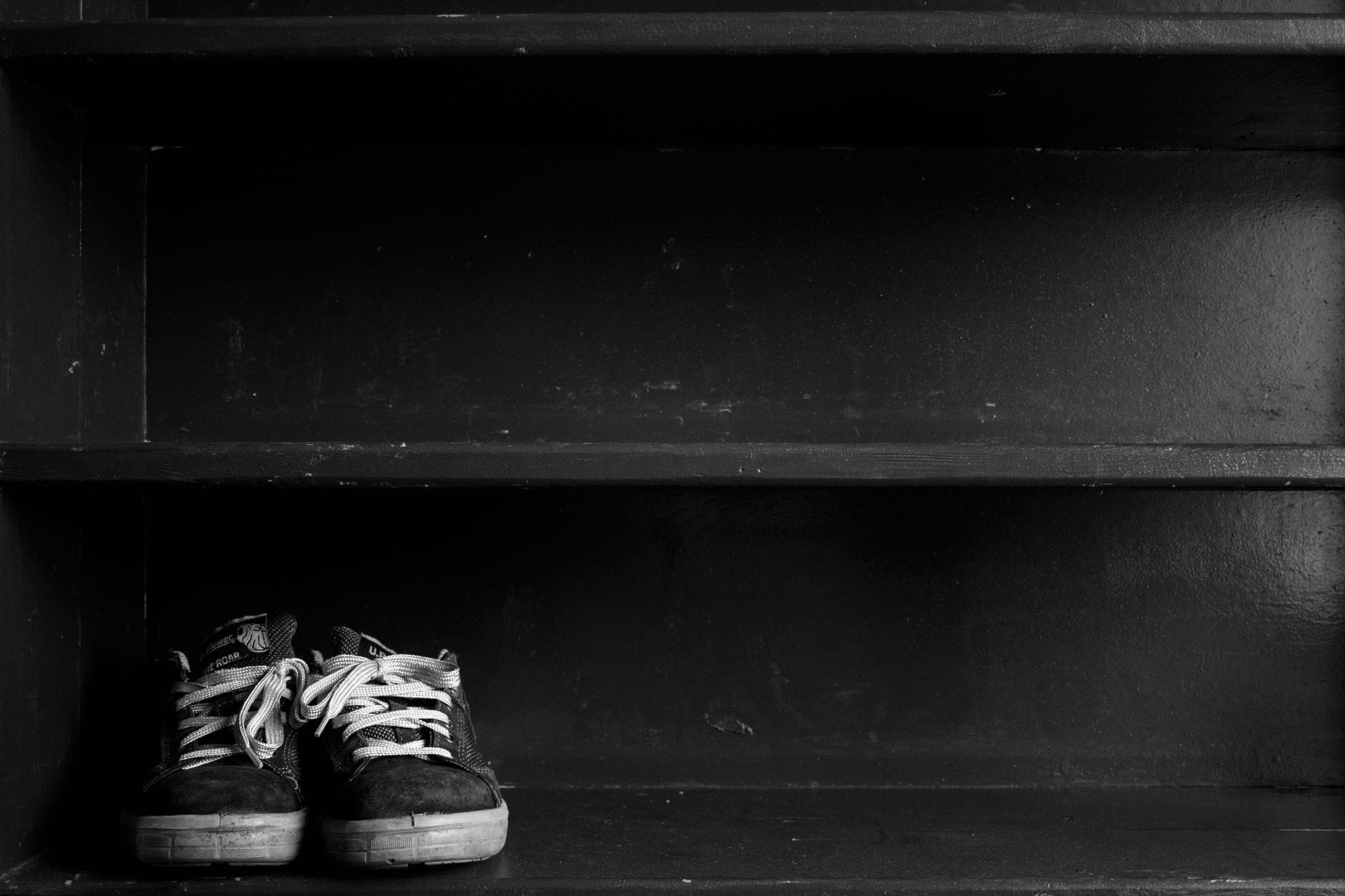 Sneakersy na ciemnej drewnianej półce w szafce na buty
